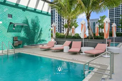 a swimming pool with pink chairs next to a building at Stylish City Retreat With Private Balcony in Miami