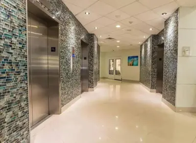 a hallway of a building with a elevator and tile walls at Dream Beach Room Free Parking - 02227 in Sunny Isles Beach