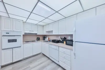 a white kitchen with white cabinets and a ceiling at Ocean reserve 1st floor across the beach STR-02382 in Sunny Isles Beach