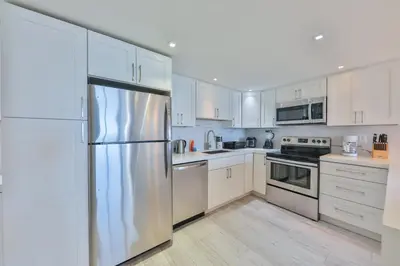 a kitchen with white cabinets and a stainless steel refrigerator at Ocean Vista in Sunny Isles Beach