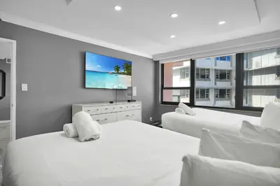a bedroom with two beds and a flat screen tv at Beachfront Luxury Alexander Unit, Pool Gym Parking in Miami Beach