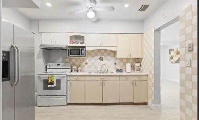 a kitchen with white cabinets and a stainless steel refrigerator at Private King Master Suite Near Hardrock Stadium in Miami Gardens