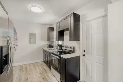 a kitchen with black and white appliances and a white door at Lauderdale Breeze Villas - Coastal 2 Bedroom in Fort Lauderdale