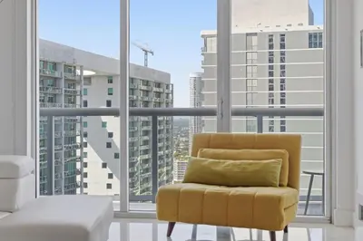 a yellow chair sitting in front of a large window at Luxury Brickell Condo with Skyline & Bay Views in Miami
