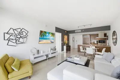 a living room with white furniture and a kitchen at Luxury Brickell Condo with Skyline & Bay Views in Miami