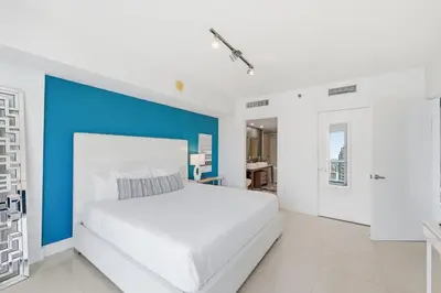 a bedroom with a large white bed and blue accent wall at Luxury Brickell Condo with Skyline & Bay Views in Miami