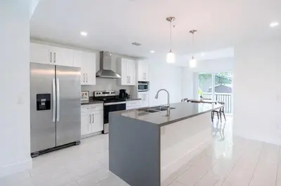 a kitchen with white cabinets and a stainless steel refrigerator at Modern 3BR Getaway 4 Beds with Free Parking Included in Hallandale Beach