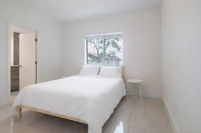 a white bed in a room with a window at Modern 3BR Getaway 4 Beds with Free Parking Included in Hallandale Beach