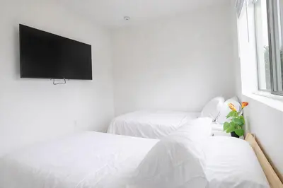 a white room with two beds and a flat screen tv at Modern 3BR Getaway 4 Beds with Free Parking Included in Hallandale Beach