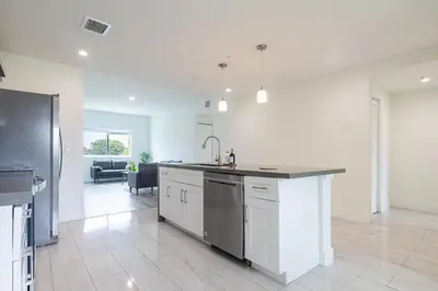 a kitchen with a counter top and a living room at Stylish 3BR Apartment, 4 Beds, Great for Groups with Free Parking in Hallandale Beach