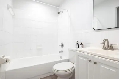 a white bathroom with a toilet and a sink at Comfy 2BR Apartment Near Las Olas with Patio, BBQ and FREE PARKING in Fort Lauderdale