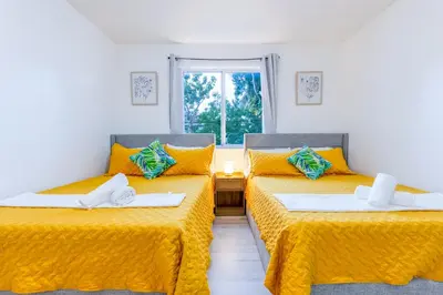 two beds in a room with yellow sheets and a window at Riverside Retreat Skyline Views & Beach Nearby in Miami