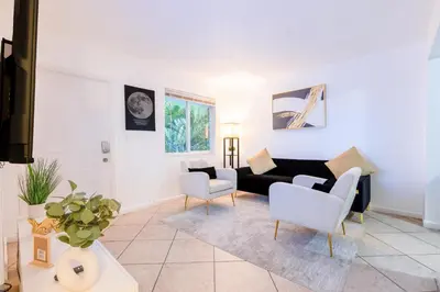 a living room with a black couch and white chairs at Riverside Retreat Skyline Views & Beach Nearby in Miami