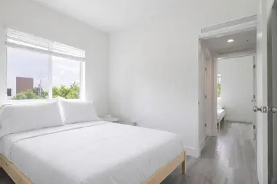 a white bedroom with a large bed and a window at Comfortable 3BR Apartment, 4 Beds, Free Parking Included in Hallandale Beach
