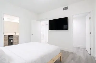 a white bedroom with a bed and a flat screen tv at Comfortable 3BR Apartment, 4 Beds, Free Parking Included in Hallandale Beach