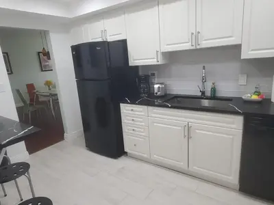 a kitchen with a black refrigerator and white cabinets at Hollywood Beach, Miami, Oceanfront retreat in Hollywood