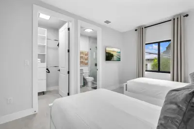 a white bedroom with two beds and a bathroom at Sandra's Place - Family - Entire 8BR-6BA in Miami
