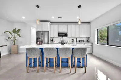 a kitchen with white cabinets and blue bar stools at Sandra's Place - Family - Entire 8BR-6BA in Miami