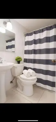 a bathroom with a blue and white shower curtain and a toilet at Santorini Wynwood in Miami