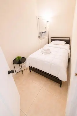 a white bedroom with a bed and a table at Santorini Wynwood in Miami