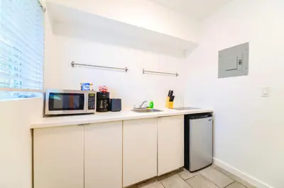 a white kitchen with a microwave and a sink at Relaxing Studio with Modern Comfort in Miami