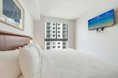 a bedroom with a white bed and a flat screen tv at Miami Highline- Sauna Heated Pool Cabanas in Miami