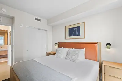 a white bedroom with a bed and a bathroom at Downtown Stay with Rooftop Pool Amenities in Miami