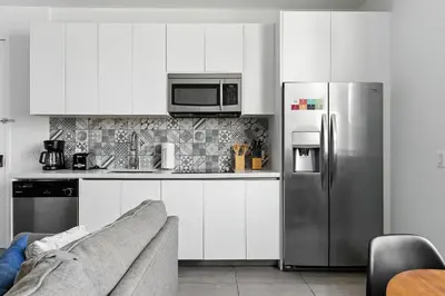 a kitchen with white cabinets and a stainless steel refrigerator at South Beach 2Q Moderno a 5 min da Praia in Miami Beach