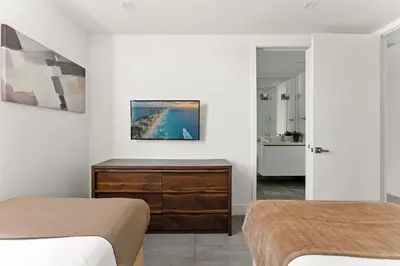 a bedroom with two beds and a dresser and a bathroom at South Beach 2Q a 5min da Praia e Vida Noturna in Miami Beach