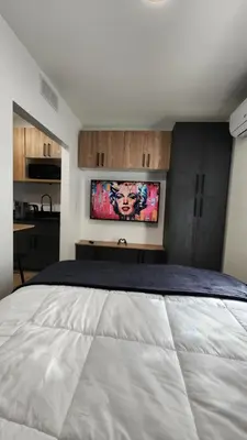 a bedroom with a large bed with a tv on the wall at Pop Art Loft in Hialeah