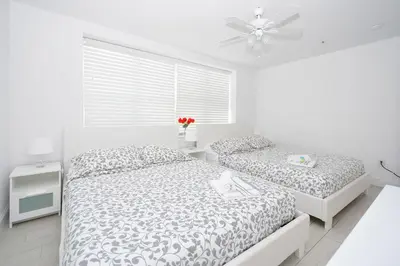 a white bedroom with two beds and a ceiling fan at Art Deco Ocean Drive Suites in Miami Beach