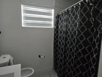 a bathroom with a black shower curtain and a toilet at Sunrise Oasis in Sunrise