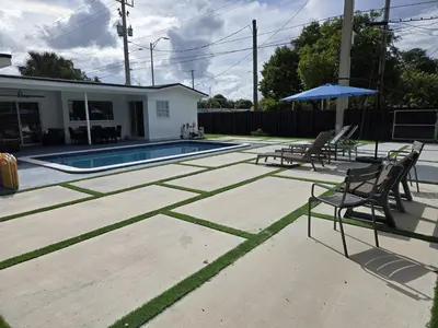 a patio with two chairs and an umbrella and a pool at Sunrise Oasis in Sunrise