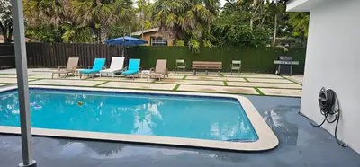 a swimming pool with lounge chairs and an umbrella at Sunrise Oasis in Sunrise