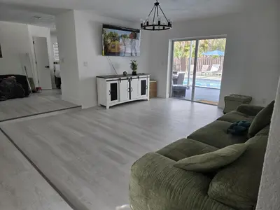 a living room with a green couch and a living room with a pool at Sunrise Oasis in Sunrise