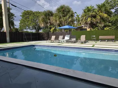 a swimming pool with chairs and a table at Sunrise Oasis in Sunrise