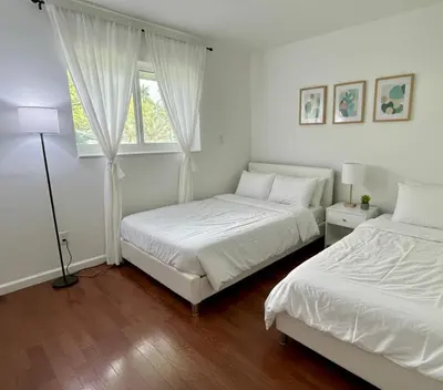 two beds in a white room with a window at House across from Baptist Hospital in Sunset Corners