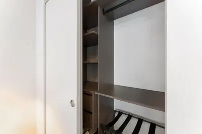 a closet with white cabinets and a wooden shelf at Crosby Miami WTC Studio Sleek #2506 in Miami