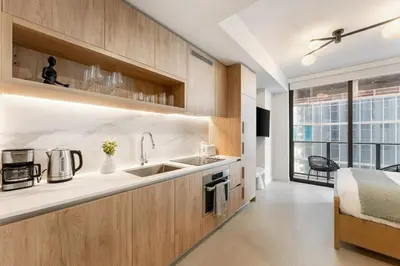 a kitchen with wooden cabinets and a sink and a bed at Crosby Miami WTC Studio Sleek #2506 in Miami