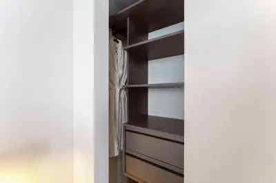 a walk in closet with dark wood shelves at Crosby Miami WTC Studio Sleek #2506 in Miami