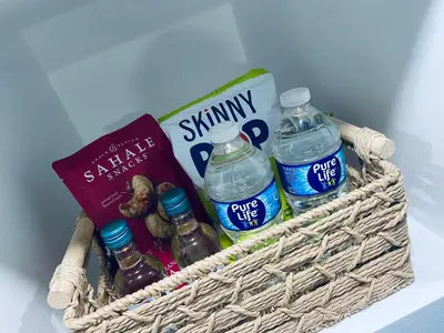 a basket with bottled water and a book and cookies at The Luxe Studio in Miami Gardens