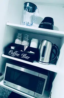 a shelf with a coffee box and a microwave at The Luxe Studio in Miami Gardens