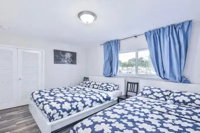 two beds in a bedroom with blue curtains at Chill Zona Arizona Villa Perfect Cruise Stay in Fort Lauderdale