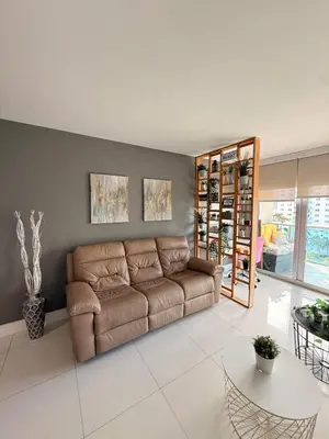 a living room with a brown couch and a table at Modern 2BR beachfront with pool & tennis view in Sunny Isles Beach