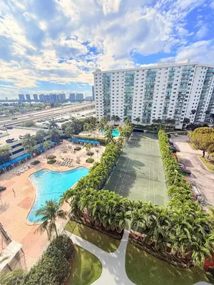 an aerial view of a resort with a pool and palm trees at Modern 2BR beachfront with pool & tennis view in Sunny Isles Beach
