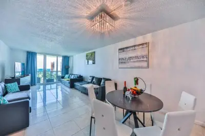 a dining room and living room with a table and chairs at Introdused by Ocean Reserve free parking STR-02559 in Sunny Isles Beach