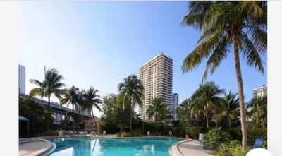 a swimming pool with palm trees and a tall building at Center of Joy in Sunny Isles Beach