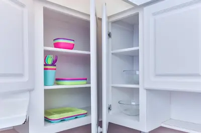 a white pantry with bowls and plates on shelves at The Elevated Above STR-02687 in Sunny Isles Beach