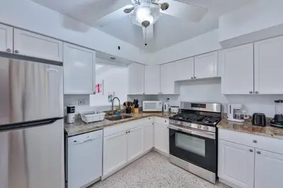 a kitchen with white cabinets and a ceiling fan at Quiet family vacation minutes from Airport in Fort Lauderdale