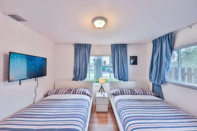 two beds in a room with blue curtains and a tv at Quiet family vacation minutes from Airport in Fort Lauderdale